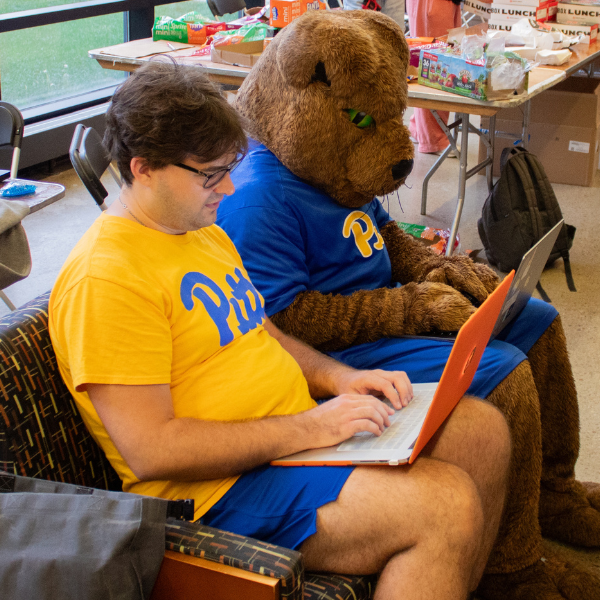 Man with laptop sits beside Roc the Panther, also on laptop